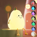 A pear silicone night lamp glowing softly on a tabletop.