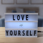 Hand placing a letter onto the magnetic surface of the black mini Cinematic Light Box.