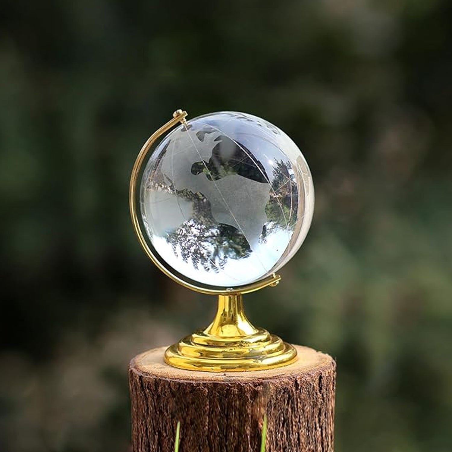 Elegant Crystal World Globe with golden stand, displayed next to a book and pen for desk decor.