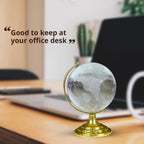 Crystal World Globe on a golden stand, viewed from an angle, highlighting its reflective surface.