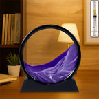 Moving Sand Art in a round glass frame, displaying a serene liquid motion sandscape on a desk.